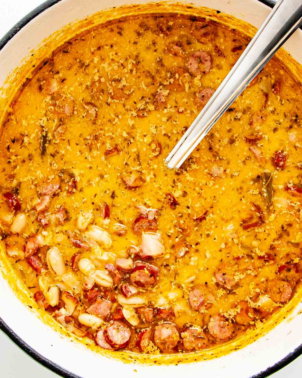 closeup overhead shot of tuscan bean soup in a dutch oven with a ladle inside