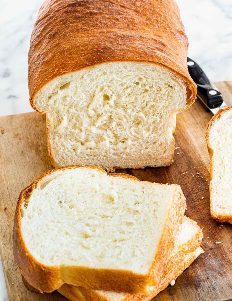 a loaf of white bread sliced on a cutting board