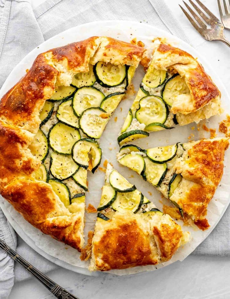 a zucchini ricotta galette on a white plate cut into slices.